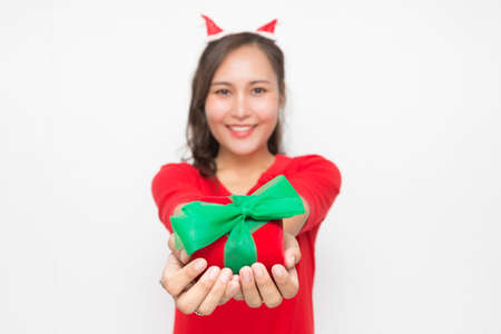 Selective focus of woman hand holding red gift box on white background. Cute Asian woman smiling and cheerful on Christmas and New Year's Day.の写真素材