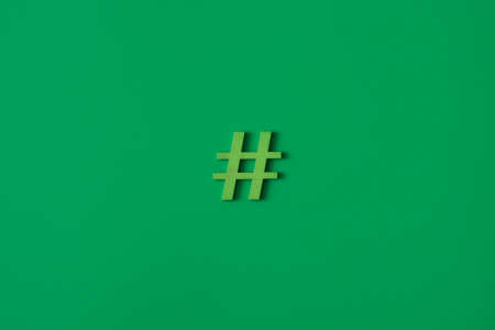 Green wooden symbol Hashtag "#" on green background and copy space for social media educational conceptの写真素材