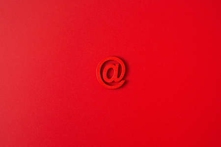 Red wooden symbol "at" on red background and copy space for social media educational conceptの写真素材
