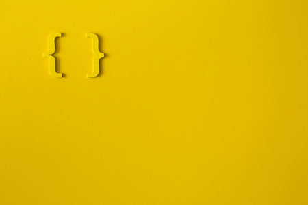 Yellow wooden symbol "bracket" on yellow background and copy space for social media educational conceptの写真素材
