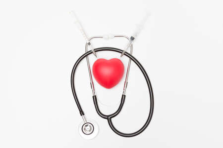 Heart was stabbed by a syringe and stethoscope on a white background and copy space for health care conceptの写真素材