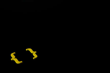 Yellow wooden symbol "bracket" on black background and copy space for social media educational conceptの写真素材