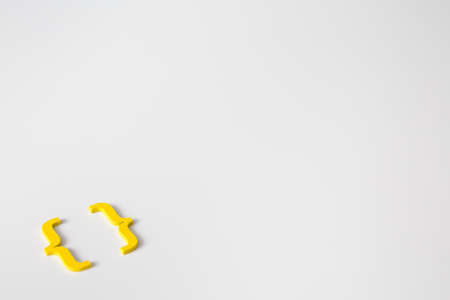 Yellow wooden symbol "bracket" on white background and copy space for social media educational conceptの写真素材