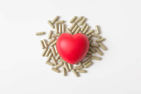 Heart shaped squeeze ball and pill capsule on white background and copy space for health care conceptの写真素材