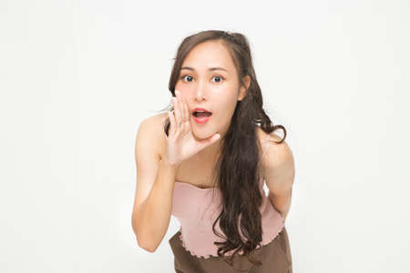 Beautiful Asian woman wearing pink casual shirt on white background. Cute Asian woman smiling and cheerful whispering somethingの写真素材