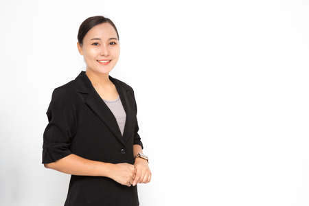 Beautiful Asian business woman wearing black suit with holding her hand on white background and copy space. Confident Asian working woman smiling and cheerfulの写真素材