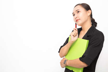 Beautiful Asian business woman wearing black suit holding document folder and pen and thinking something on white background and copy space. Confident Asian working woman smiling and cheerfulの写真素材