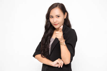Beautiful Asian business woman wearing black suit pointing finger at camera presenting something on white background and copy space. Confident Asian working woman smiling and cheerfulの写真素材