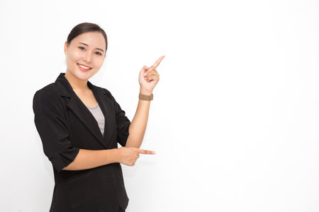 Beautiful Asian business woman wearing black suit presenting something on white background and copy space. Confident Asian working woman smiling and cheerfulの写真素材