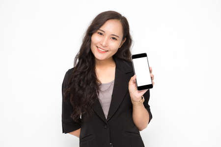 Beautiful Asian business woman wearing black suit hand holding a smartphone presenting something on white background and copy space. Confident Asian working woman smiling and cheerfulの写真素材