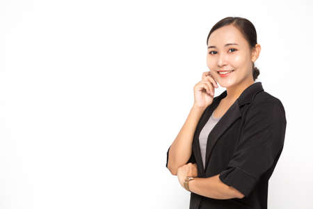 Beautiful Asian business woman wearing black suit with her crossed arms on white background and copy space. Confident Asian working woman smiling and cheerfulの写真素材
