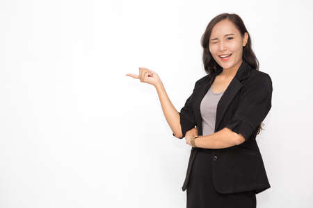 Beautiful Asian business woman wearing black suit presenting something on white background and copy space. Confident Asian working woman smiling and cheerfulの写真素材