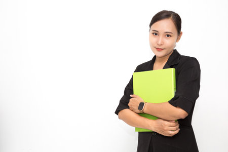 Beautiful Asian business woman wearing black suit holding document folder smiling on white background and copy space. Confident Asian working woman smiling and cheerfulの写真素材