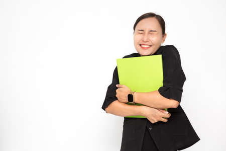 Beautiful Asian business woman wearing black suit holding document folder and happy with success something on white background and copy space. Confident Asian working woman smiling and cheerfulの写真素材