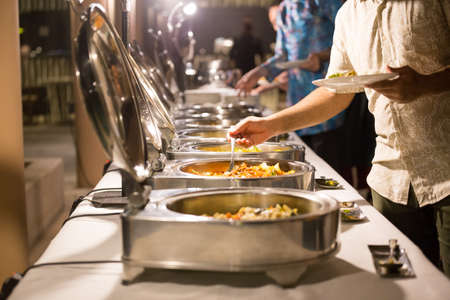 People are scooping food from chafing dishes on the table at the luxury banquet.の写真素材