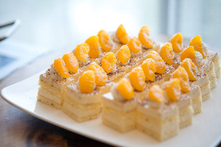 Selective focus of Orange sponge cake on white dish on the buffet table.の写真素材
