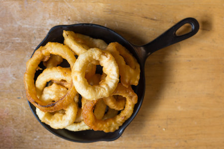 Top view of Onion rings in black plate on the wood table in restaurant.