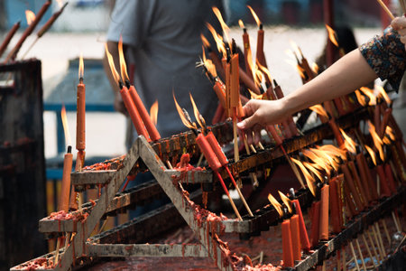 old Woman lighting prayer candle at chinese temple