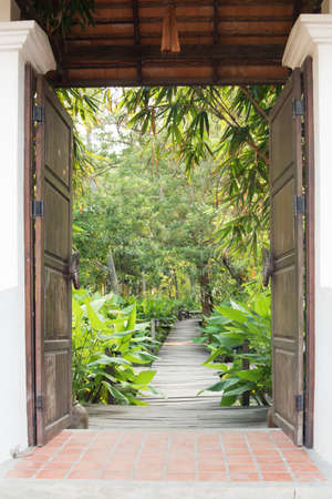 ornamental wooden door gate open to tropical garden styleの写真素材
