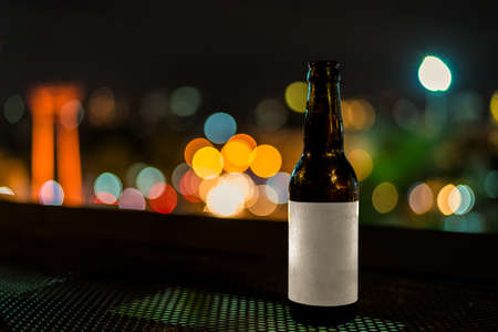 mockup blank label cold glass bottles of beer with night light bokeh backgroundの写真素材