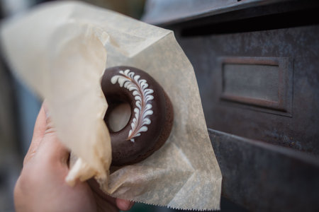 very delicious chocolate donut with rosetta art holding in paper wrap  with rust backgroundの写真素材