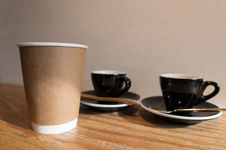 morning sunlight lighting, blank take away coffee paper cup with  espresso in ceramic cup background on wooden tableの写真素材