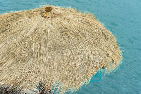 yellow hay roof umbrella with blue sea background in summer seasonの写真素材