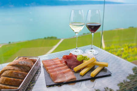 white wine and red wine with mix snack , cheese ,smoked ham salami platter and bread at vineyardの写真素材