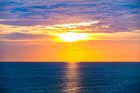 panorama view of sunset twilight sky and sea ocean on summer season with tiny sillhouette fishing boat at far awayの写真素材