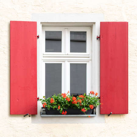 vintage red wooden window exterior with flower bed outsideの写真素材