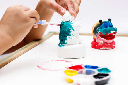 The kid painting color on the plaster statueの写真素材