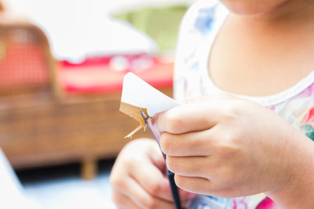 The little girl is cutting color paper. The little girl makes handcraft.の写真素材