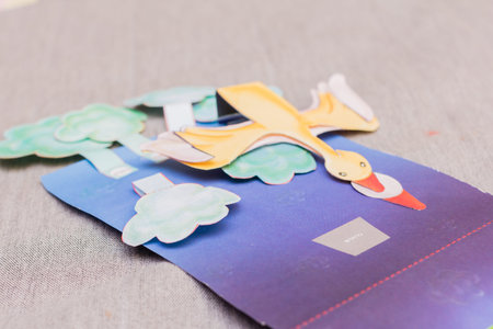 The little girl is gluing color paper. The little girl makes handcraft.
