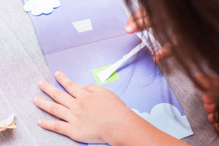 The little girl is gluing color paper. The little girl makes handcraft.の写真素材