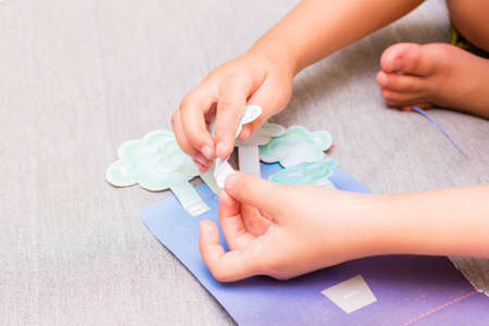 The little girl is gluing color paper. The little girl makes handcraft.の写真素材