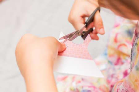 The little girl is cutting color paper. The little girl makes handcraft.の写真素材