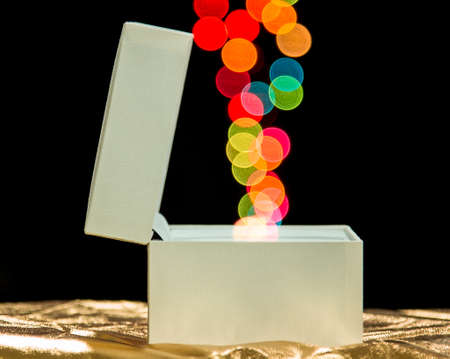 White gift box on dark background with colour bokehの写真素材