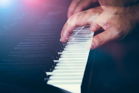 Musician's hand is playing a keyboard in low light backgroundの写真素材