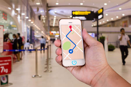 Man is holding mobile phone with map gps navigation in the airport.の写真素材