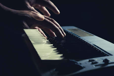 Musician's hand is playing a keyboard in low light backgroundの写真素材