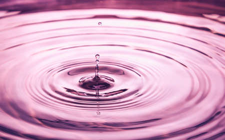 The wave from water drop in gold backgroundの写真素材