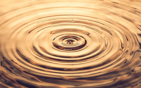 The wave from water drop in gold backgroundの写真素材