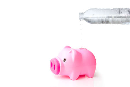 Isolate water bottle saving water in to pink piggybank on the white backgroundの写真素材