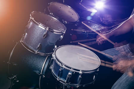 The man is playing drum set in low light background.の写真素材