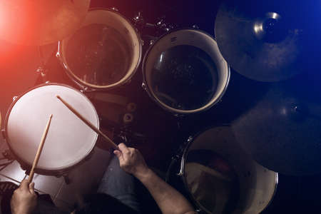 The man is playing drum set in low light background.の写真素材