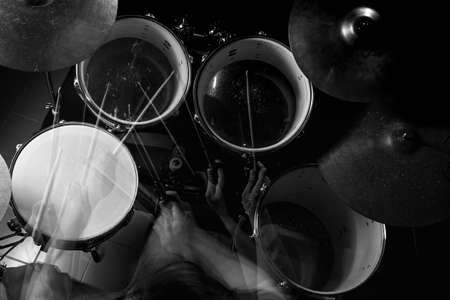 The man is playing drum set in low light background, black and white.の写真素材