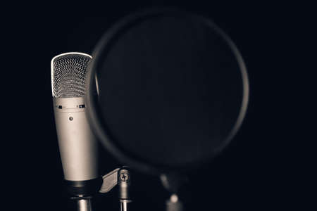Professional condenser microphone with pop filter in black backgroundの写真素材