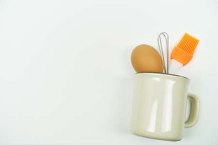 preparing food, Fresh eggs with Whisk in a white cup on white background.の写真素材