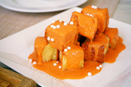 Toast, a piece of square bread baked with butter, topped Thai Milk Tea sauce and decorated with a...