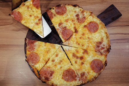 Fast Food,A thin crust pepperoni pizza was cut to eight triangle pieces and separated from others, that placed on rounded wooden tray.の写真素材